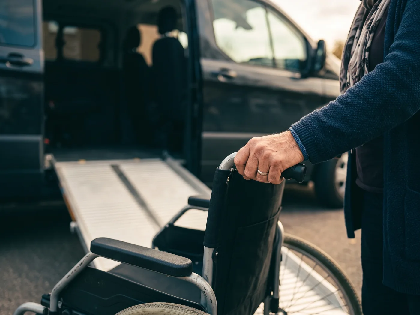 Osoba przygotowująca wózek przy rampie prowadzącej do pojazdu
